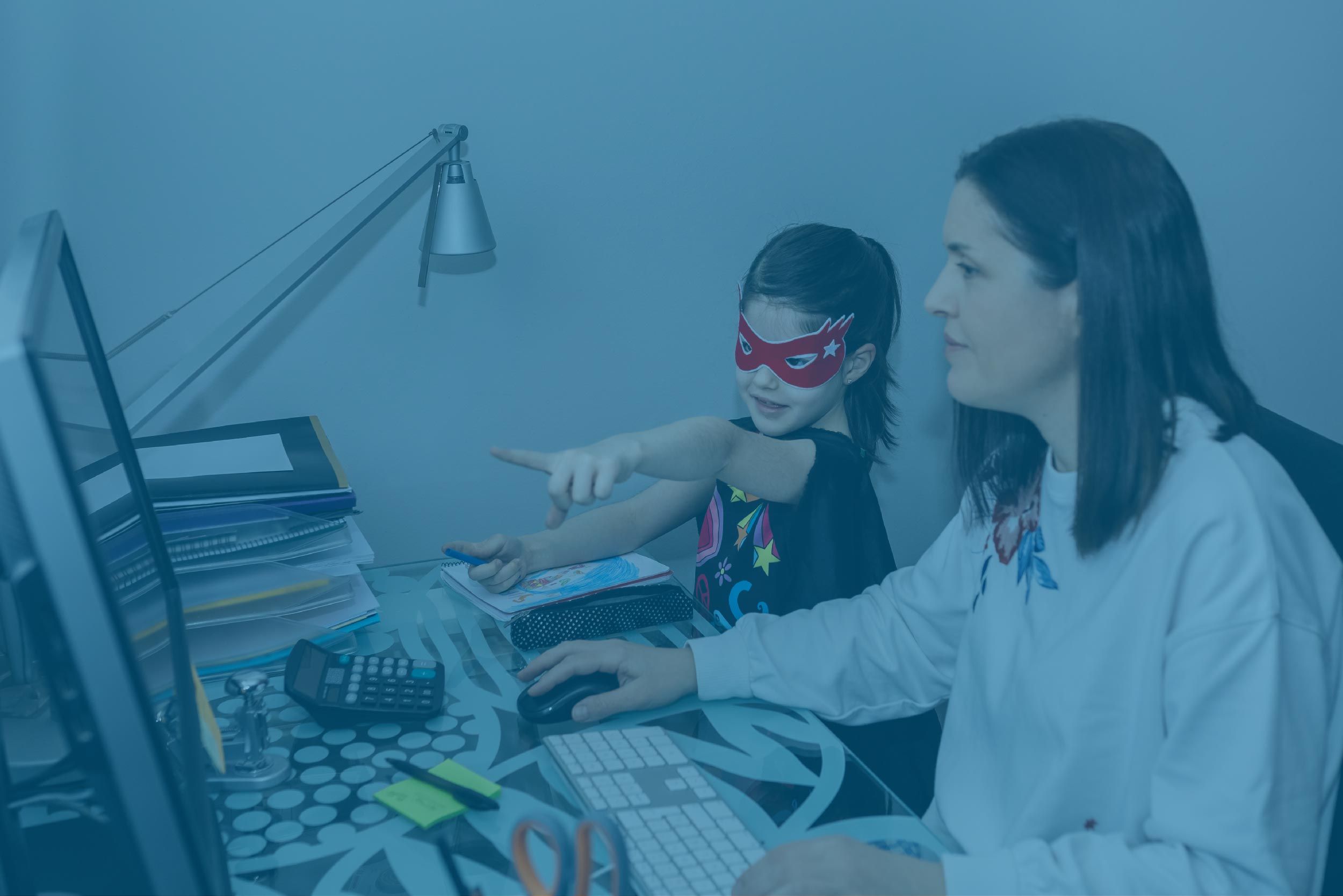 Une petite fille avec une femme qui travaille devant son ordinateur