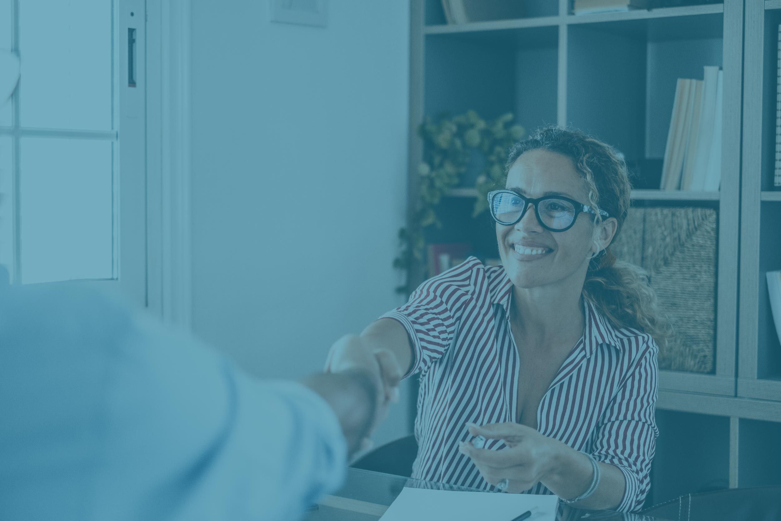 Femme souriante serrant la main d'un homme lors d'un entretien d'embauche